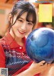 A woman holding a blue bowling ball in her hands.