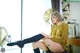 A woman sitting on top of a stool next to a window.