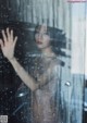 A woman standing in front of a shower in the rain.