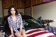 A woman sitting on top of a car covered in an American flag.