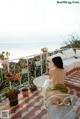 A woman sitting on a balcony with a view of the ocean.