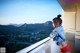 A woman in a red bikini and denim jacket standing on a balcony.