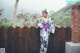 A woman in a kimono standing in front of a wooden fence.