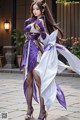 A woman in a purple and white dress is posing for a picture.