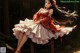 A woman in a red and white dress sitting on a wooden bench.