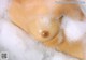 A close up of a mannequin in a bathtub filled with foam.
