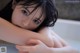 A woman in a bathtub with wet hair and blue eyes.